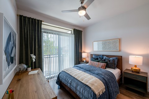 A bedroom with a bed, nightstand, and a painting on the wall.