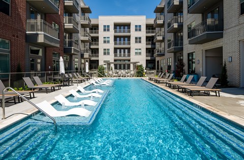 A long rectangular pool with lounge chairs on either side.