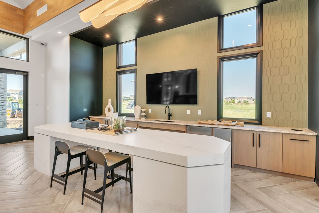 A modern kitchen with a bar area and a television mounted on the wall.