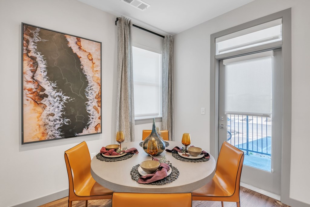 A dining room with a large painting on the wall and a table set for a meal.