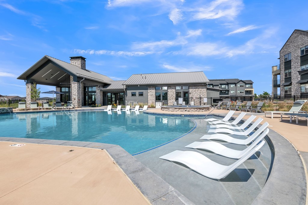 A large swimming pool with lounge chairs and a building in the background.