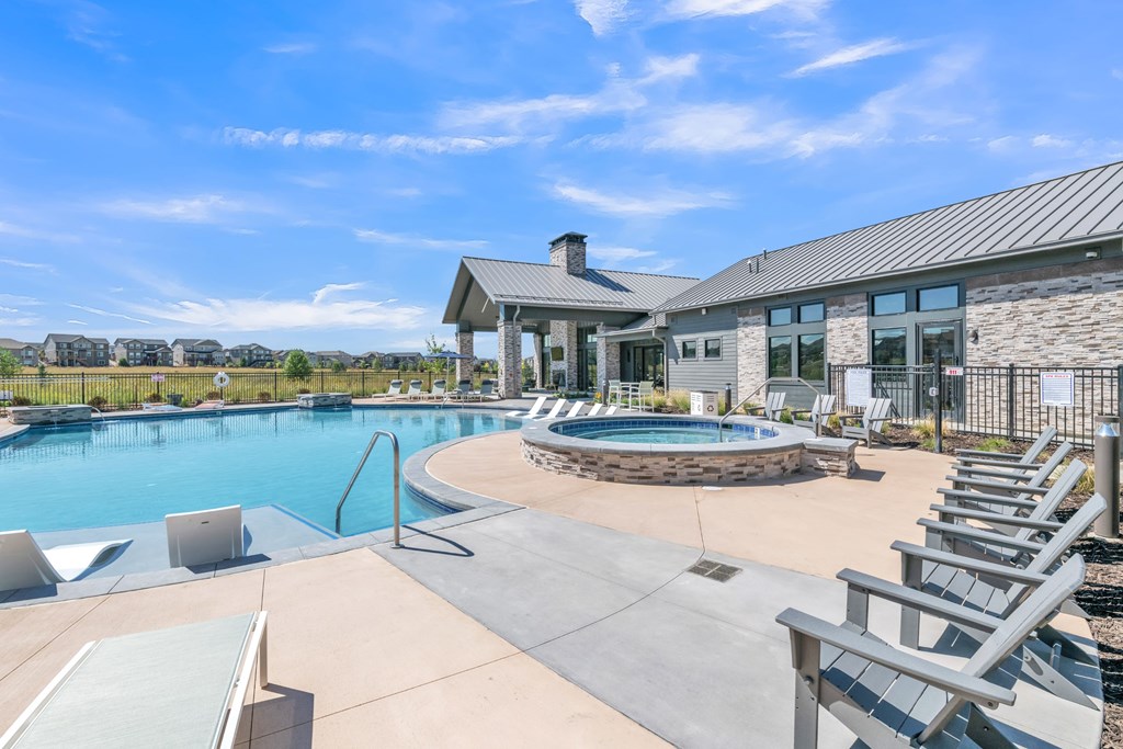 A large outdoor swimming pool with lounge chairs and a building in the background.
