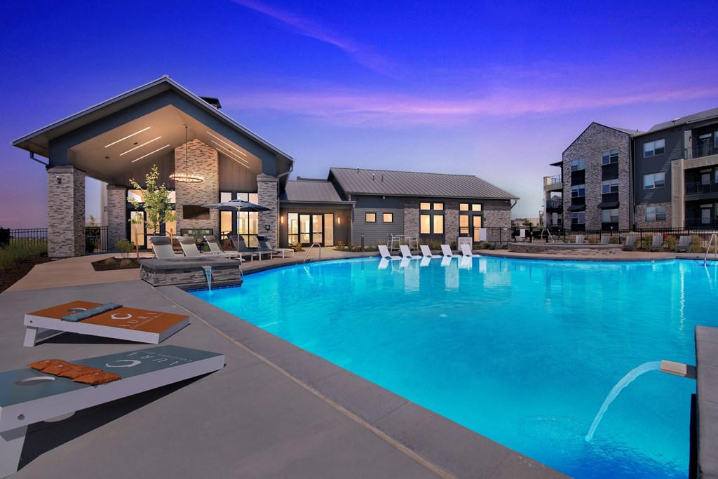 A swimming pool with lounge chairs and a building in the background.