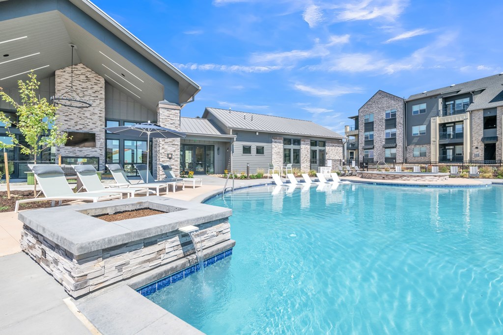 A large swimming pool with a stone bench in front of a modern building.