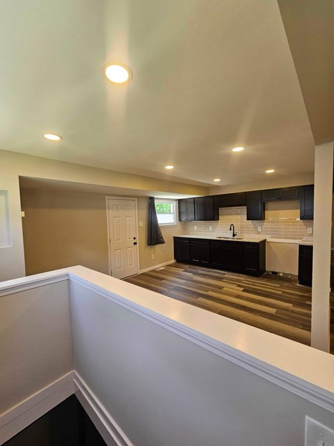A well-lit kitchen with dark wood floors and white walls.