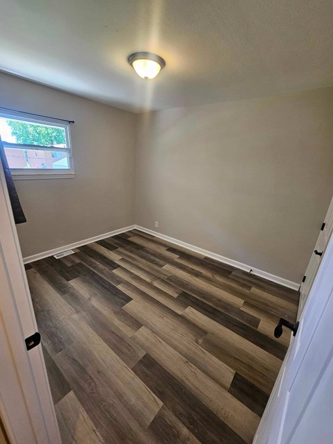 A room with wooden flooring and a window.