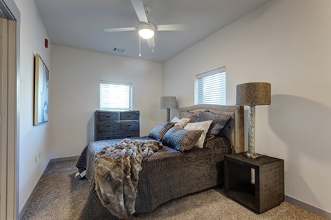 A bedroom with a bed, a lamp, and a ceiling fan.