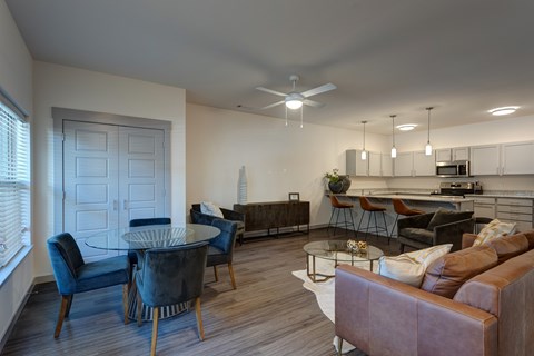 A modern living room with a glass table and brown couch.