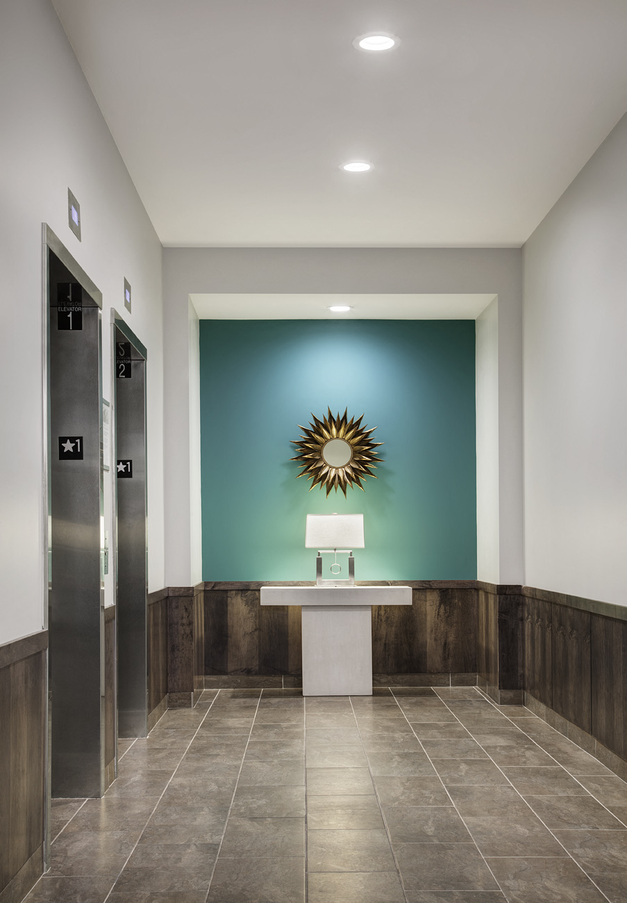 a hallway with a urinal and a green wall with a sunburst