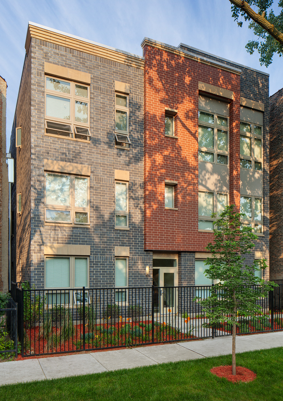 a brick apartment building with a sidewalk in front of it