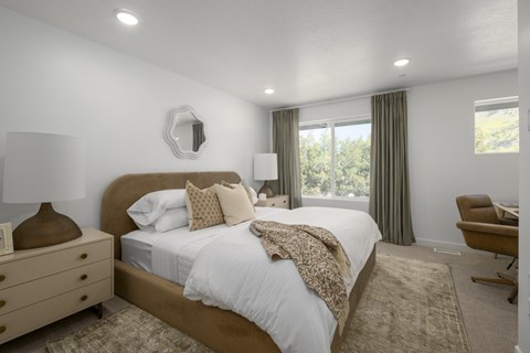 A bedroom with a large bed and a chair.