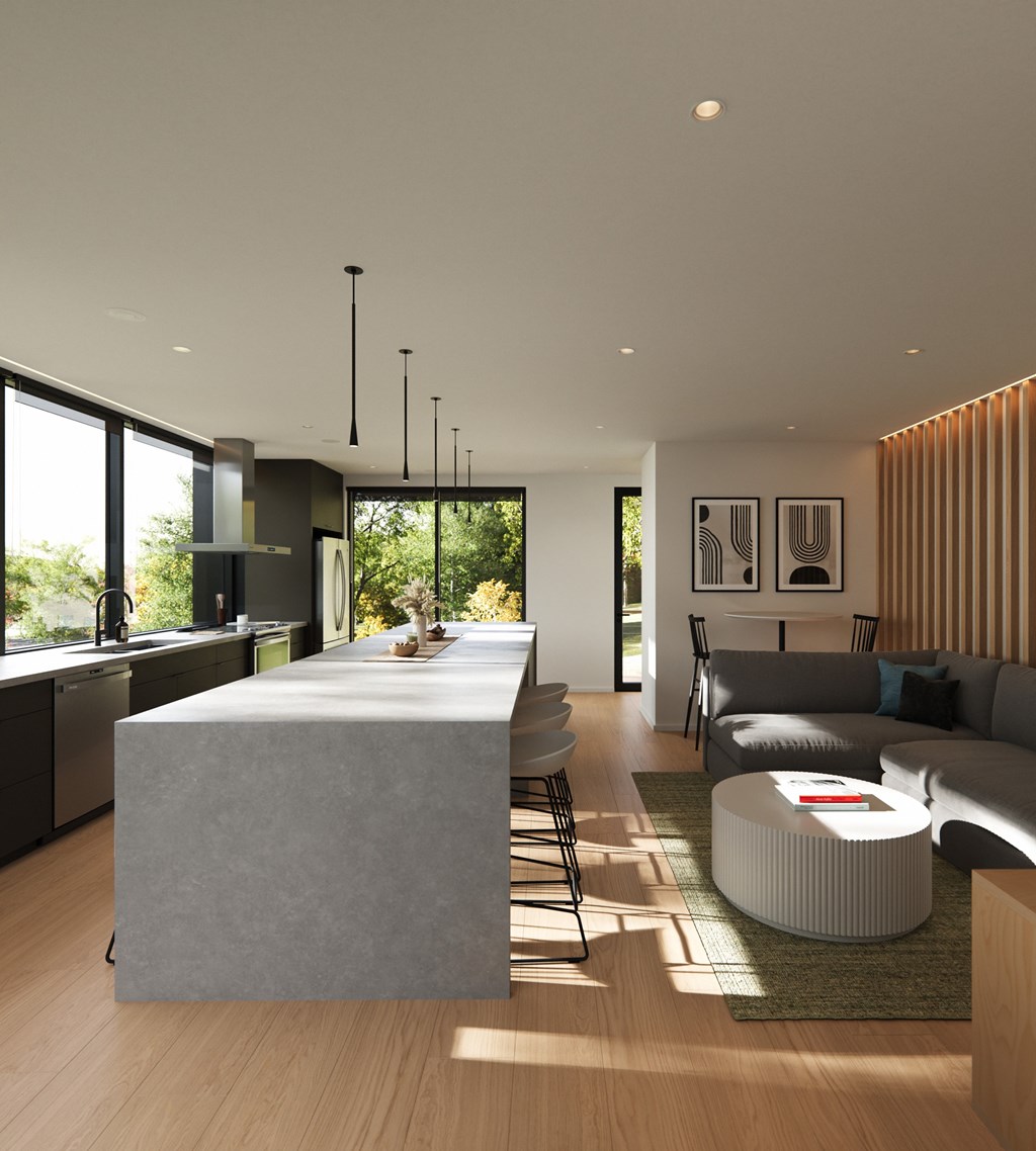 A modern kitchen with a large island and a living room with a grey couch.