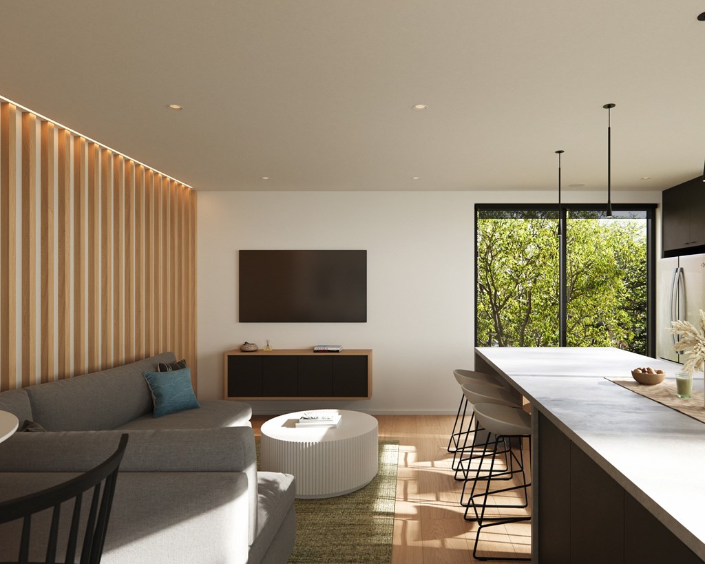 A modern living room with a grey sofa, a white coffee table, and a flat screen TV mounted on the wall.