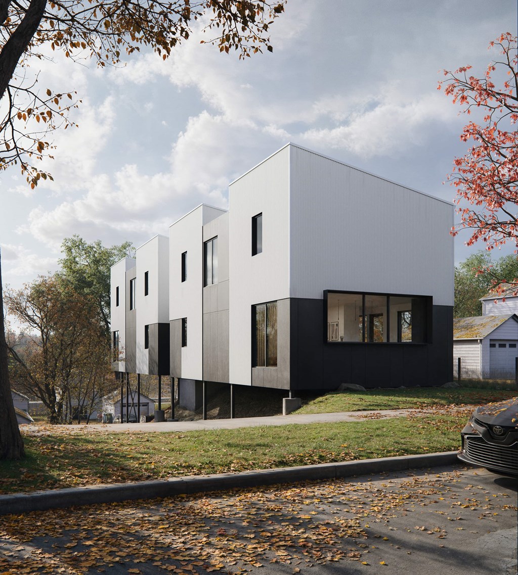 A modern white building with black windows is surrounded by trees with autumn leaves.