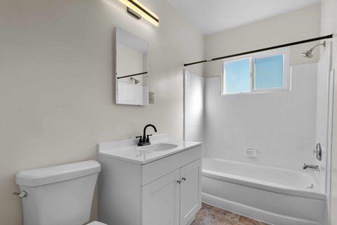 A white bathroom with a toilet, sink, and bathtub.