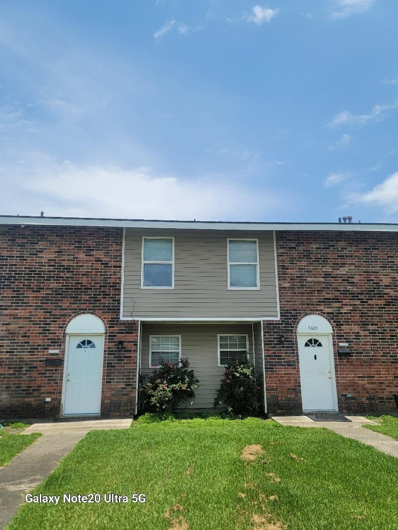 A brick house with a grey front and two white doors.