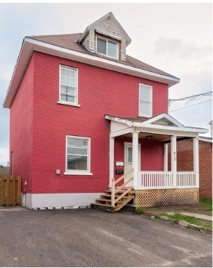 A red brick house with a white porch.