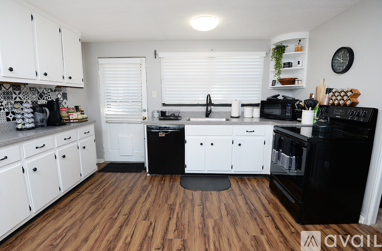 A kitchen with white cabinets and black appliances.