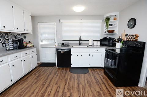 A kitchen with white cabinets and black appliances.