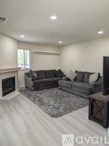 A living room with a grey couch and a fireplace.