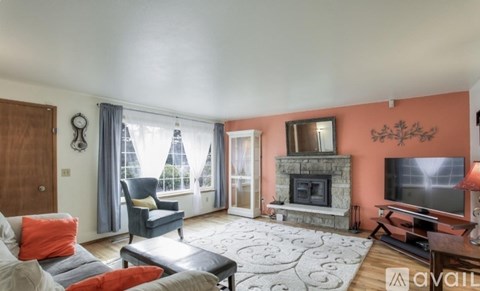 A living room with a grey sofa and a grey armchair with orange pillows.