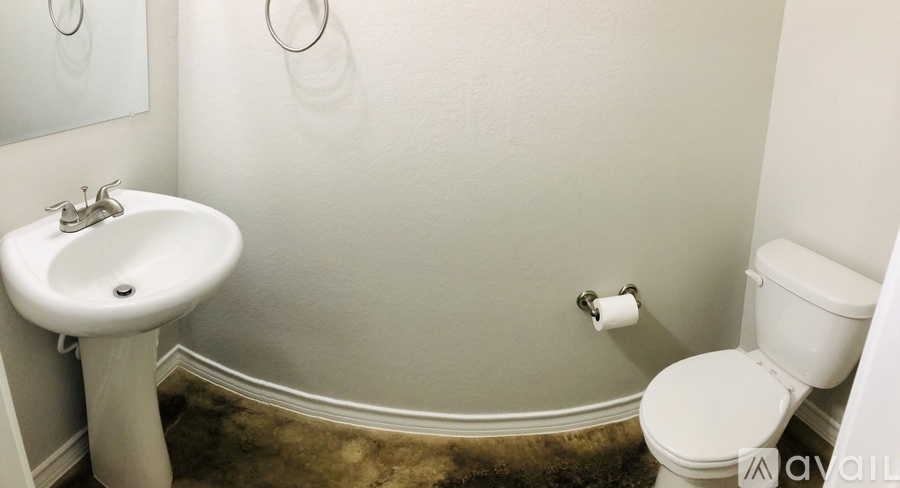 A bathroom with a toilet, sink, and a roll of toilet paper.