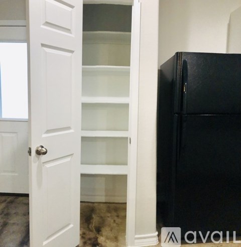 A black refrigerator is in a kitchen next to a white door.