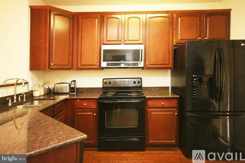 A kitchen with wooden cabinets and black appliances.