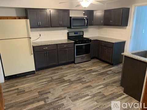 A kitchen with wooden flooring and a white refrigerator.