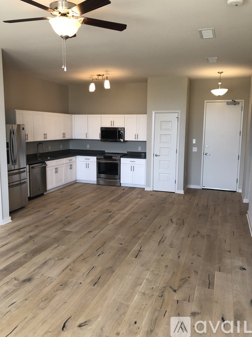 A kitchen with wooden floors and a ceiling fan.