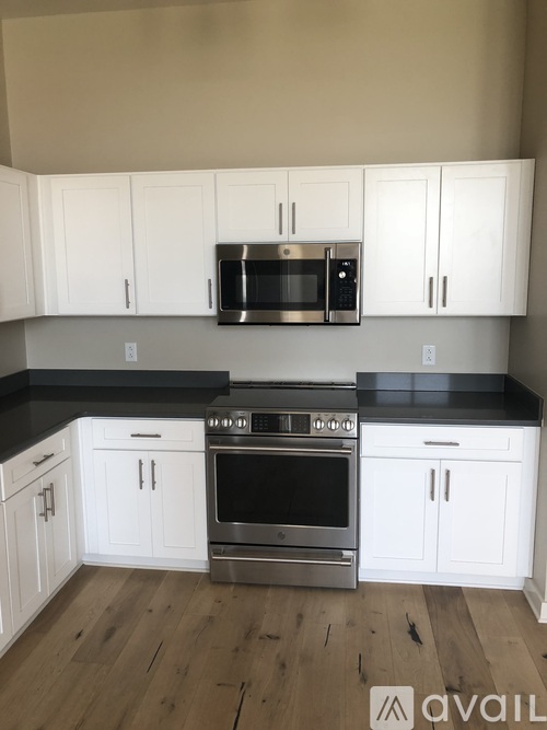 A kitchen with white cabinets and black countertops.