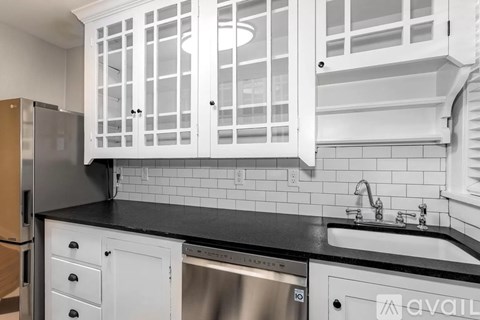 A kitchen with white cabinets and a black countertop.