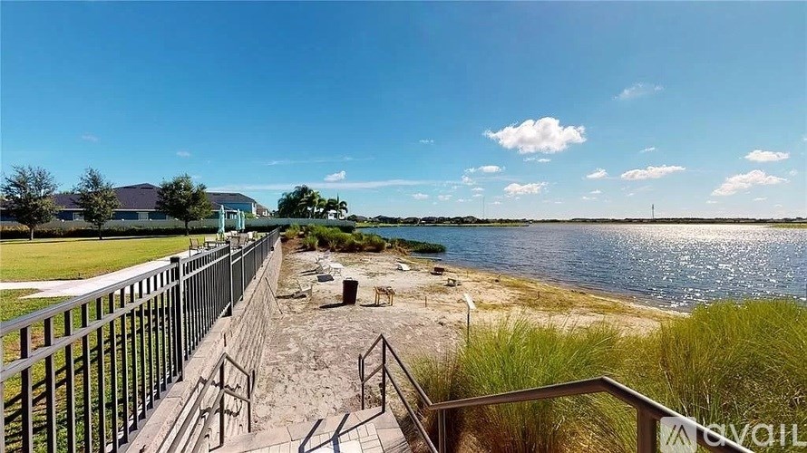 A view of a beach with a metal railing and steps leading down to the sand.