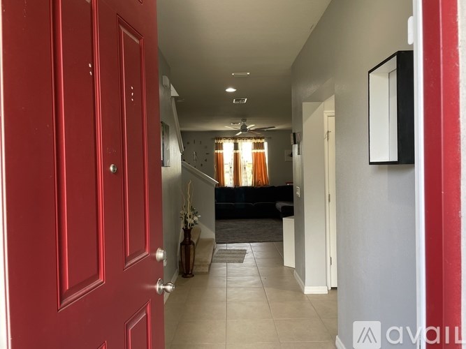 A hallway with a red door leading to a living room.
