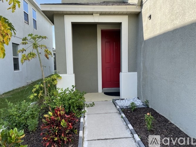 A red door is the centerpiece of a small front yard.