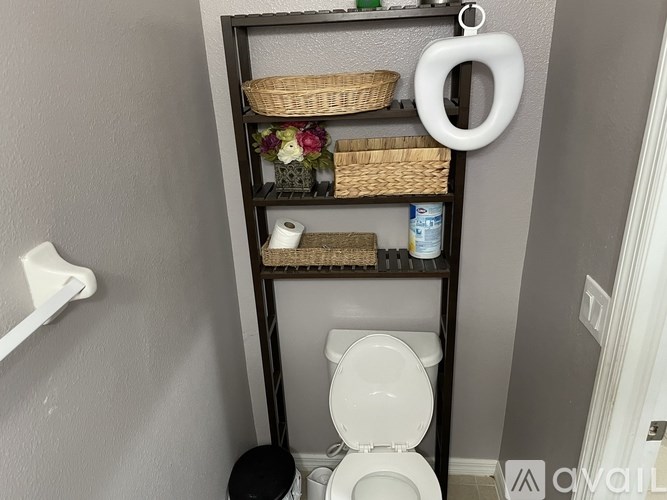 A white toilet is in a bathroom with a shelf above it.