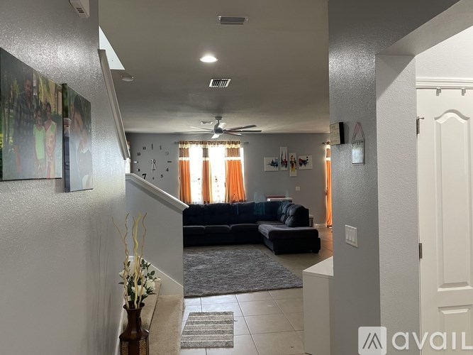 A living room with a black sofa and a grey rug.