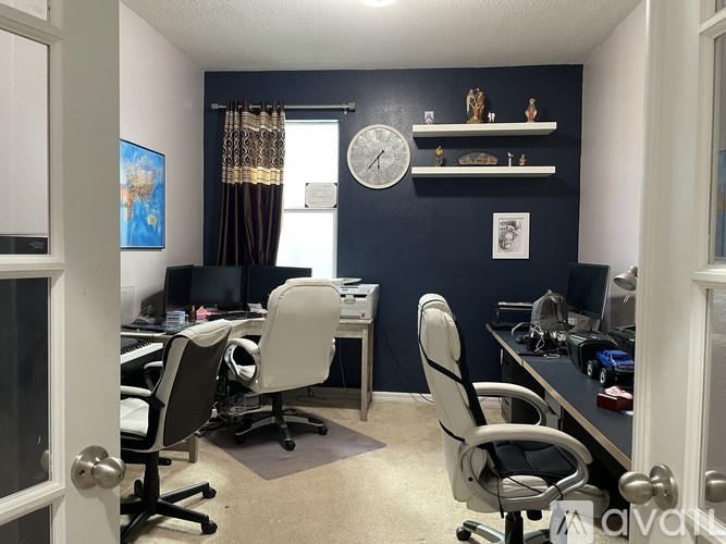 A room with a desk and chairs in front of a window.