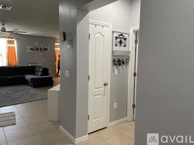 A hallway with a white door and a black couch in the background.