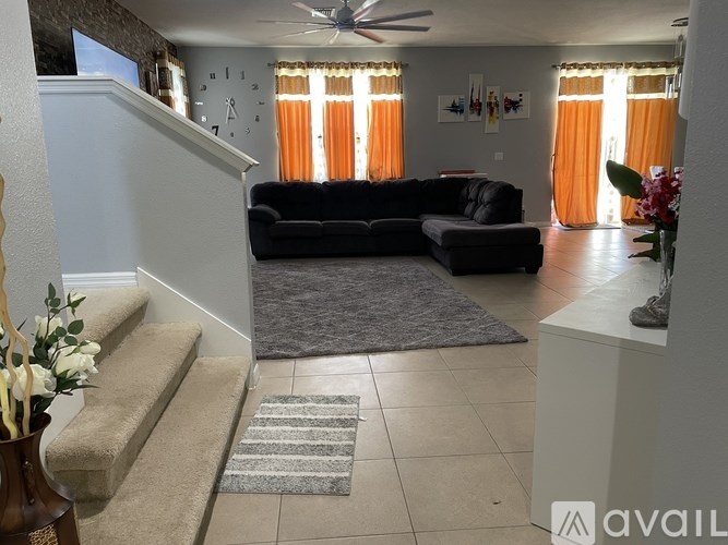 A living room with a black couch and a fan on the wall.