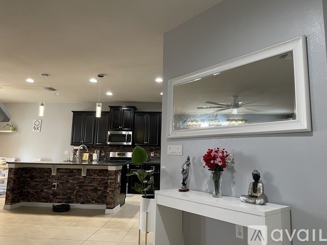 A modern kitchen with a stone counter and a large mirror above it.