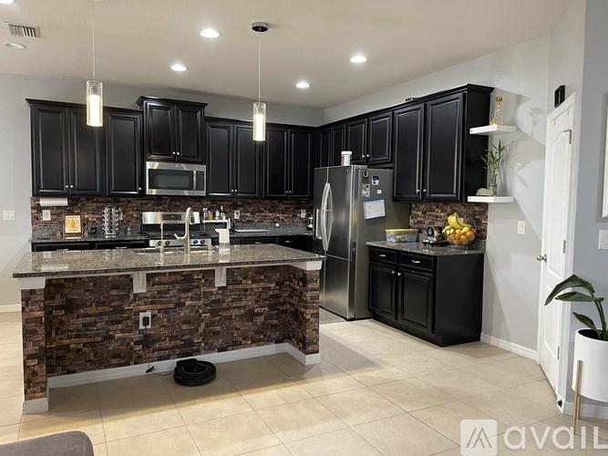 A kitchen with black cabinets and a stone counter.