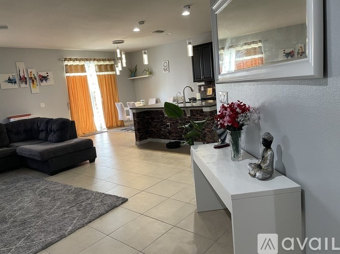 A living room with a black couch, a white bench, and a large mirror on the wall.