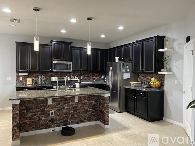 A kitchen with black cabinets and a stone counter.