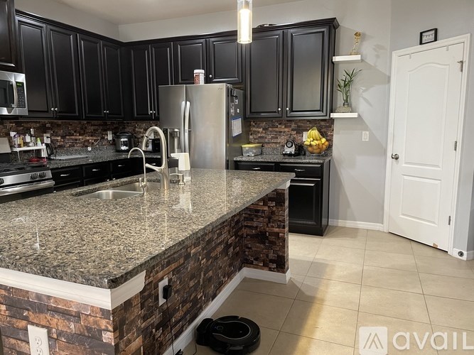 A kitchen with black cabinets and a granite countertop.