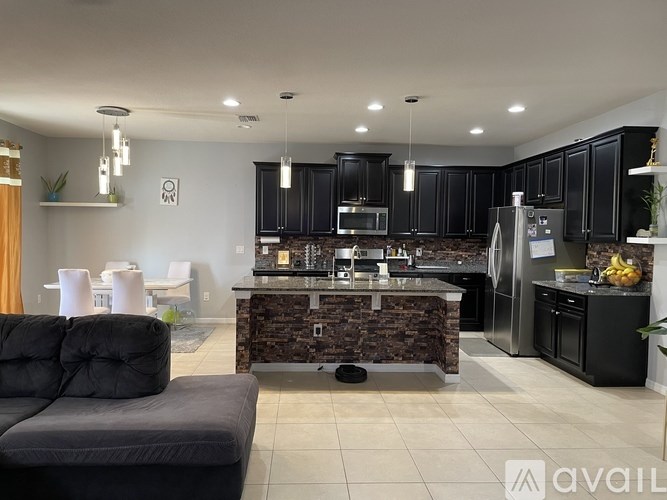 A modern kitchen with black cabinets and a stone backsplash.
