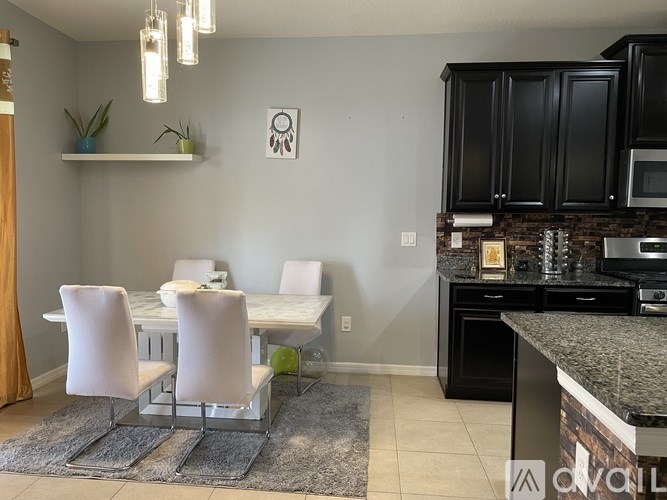 A kitchen with black cabinets and a white table.