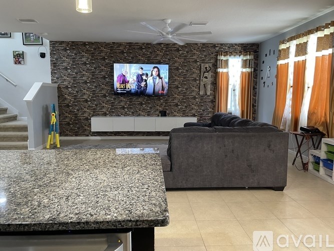 A living room with a stone wall and a flat screen TV mounted on it.