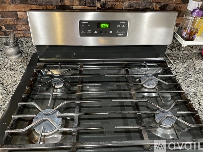 A modern stainless steel gas stove with four burners and a digital control panel.