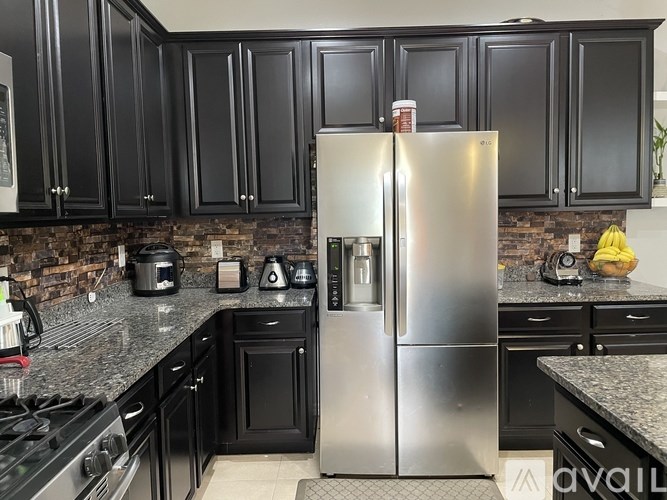 A kitchen with black cabinets and a stainless steel refrigerator.